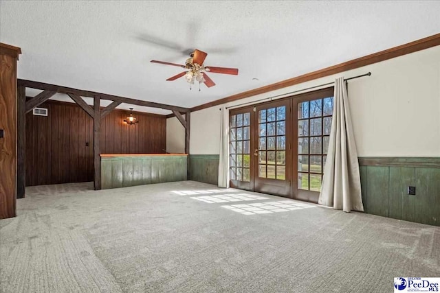 unfurnished living room featuring carpet floors, a wainscoted wall, wooden walls, and a textured ceiling