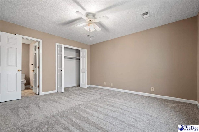 unfurnished bedroom with a textured ceiling, carpet floors, visible vents, and baseboards