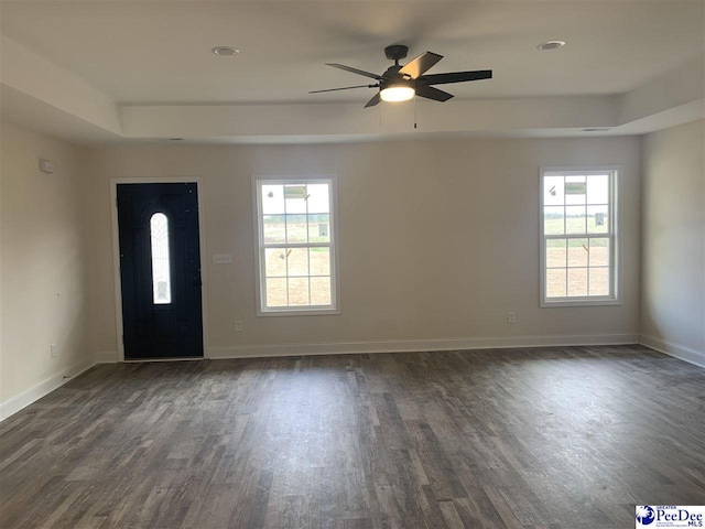 foyer entrance featuring a ceiling fan, a raised ceiling, baseboards, and dark wood-style flooring