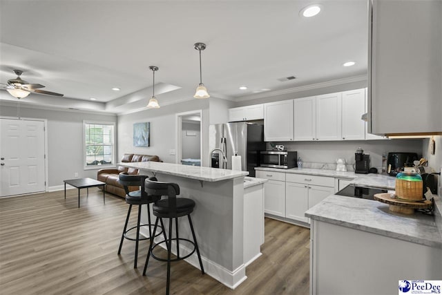 515 Young St, Darlington, SC 29532 - kitchen featuring appliances with stainless steel finishes, open floor plan, a breakfast bar area, wood finished floors, and white cabinets