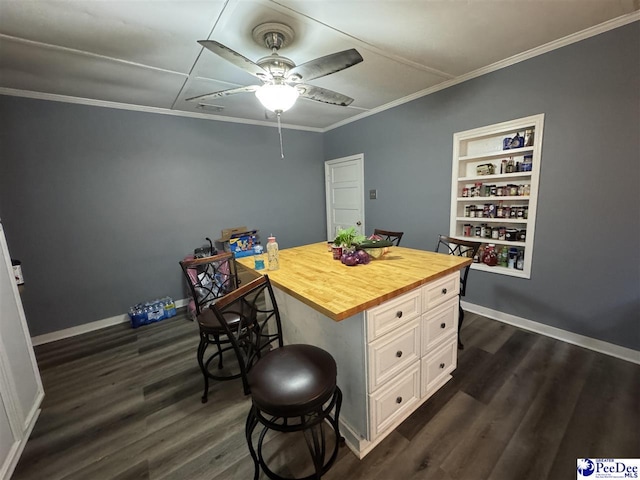 dining area featuring dark wood-type flooring, a ceiling fan, ornamental molding, and built in features