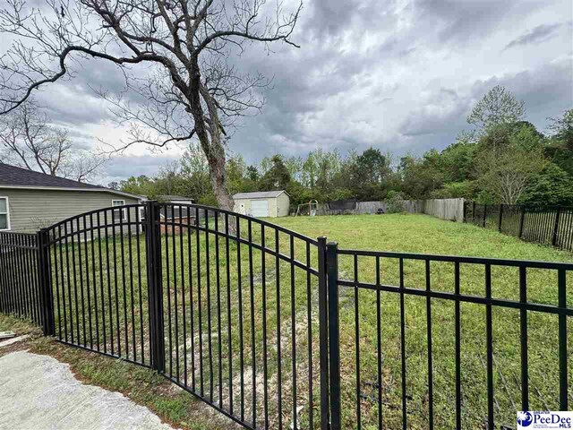 view of gate with a fenced backyard and a yard
