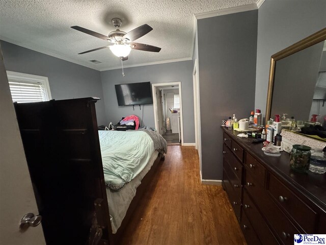 bedroom with a textured ceiling, crown molding, visible vents, baseboards, and dark wood-style flooring