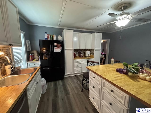 kitchen featuring a sink, decorative backsplash, ceiling fan, black fridge, and butcher block counters