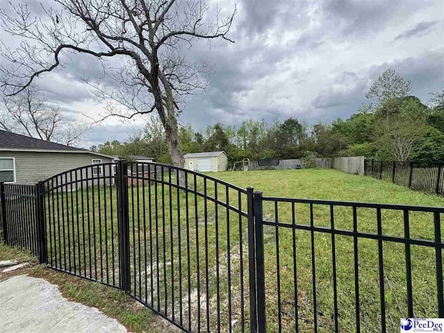 view of gate with a yard and a fenced backyard