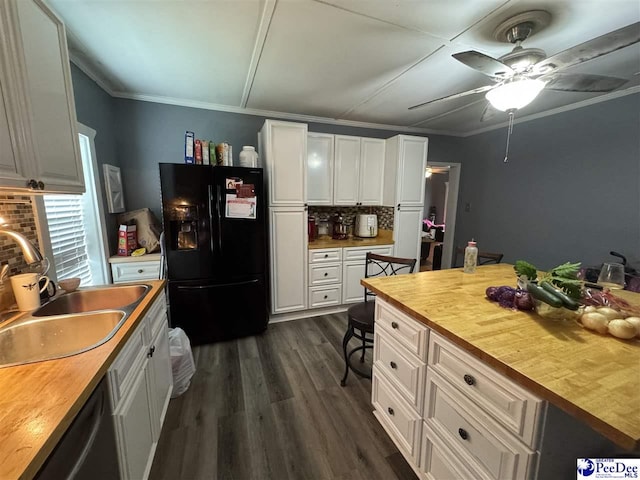 kitchen with decorative backsplash, black fridge with ice dispenser, white cabinets, a sink, and wooden counters
