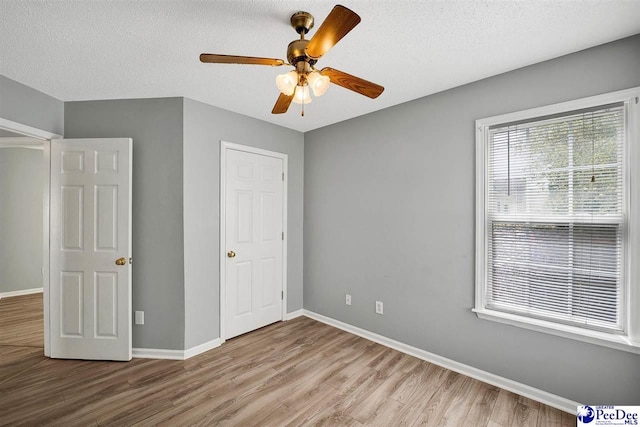 unfurnished bedroom featuring ceiling fan, light hardwood / wood-style flooring, and a textured ceiling