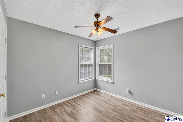 empty room with ceiling fan, a textured ceiling, and light wood-type flooring