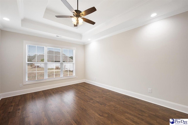 spare room with a tray ceiling, dark wood-type flooring, ornamental molding, and ceiling fan