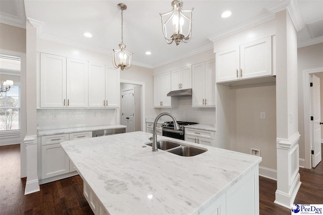 kitchen with white cabinetry, sink, hanging light fixtures, a kitchen island with sink, and light stone counters