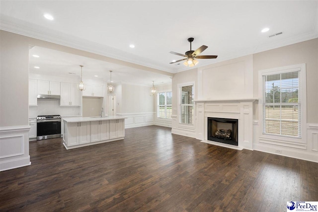 unfurnished living room with crown molding, ceiling fan, dark hardwood / wood-style floors, and sink