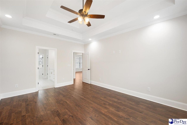 spare room with dark wood-type flooring, ceiling fan, crown molding, and a raised ceiling