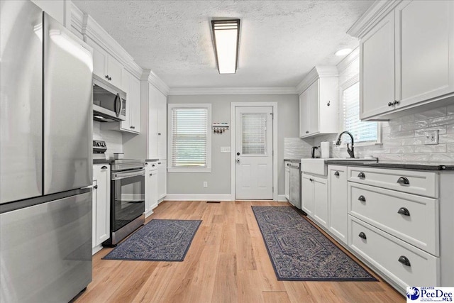 3900 Claussen Rd, Florence, SC 29505 - kitchen with stainless steel appliances, ornamental molding, decorative backsplash, white cabinetry, and a textured ceiling