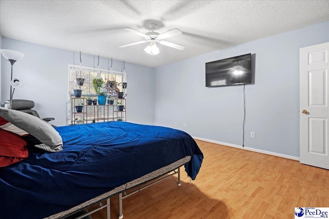 bedroom with hardwood / wood-style flooring, ceiling fan, and a textured ceiling