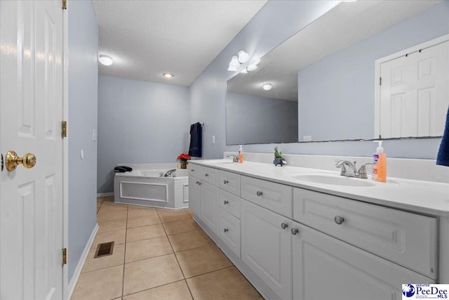 bathroom featuring vanity, tile patterned flooring, a textured ceiling, and a washtub