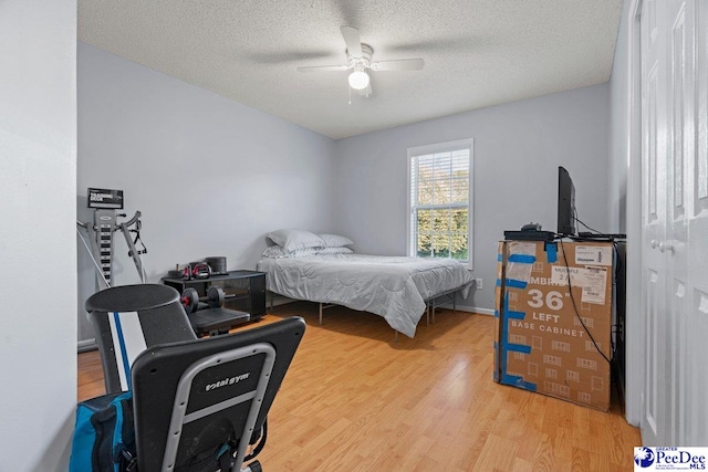 bedroom with ceiling fan, light hardwood / wood-style flooring, and a textured ceiling