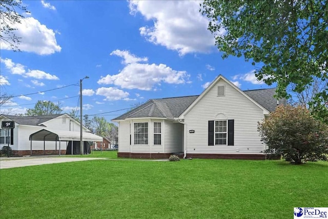 813 Williams St, Lake City, SC 29560 - view of front facade with a front lawn, a detached carport, roof with shingles, and driveway