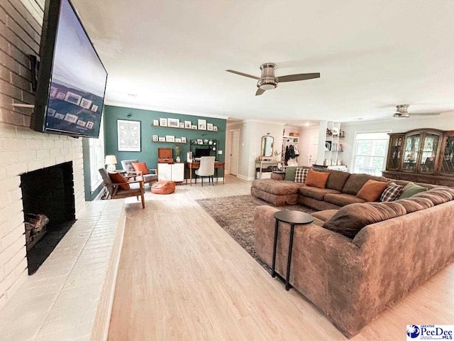 living room featuring a ceiling fan, wood finished floors, a fireplace, and ornamental molding