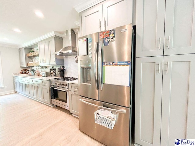 kitchen with stainless steel appliances, wall chimney range hood, open shelves, light wood finished floors, and light countertops