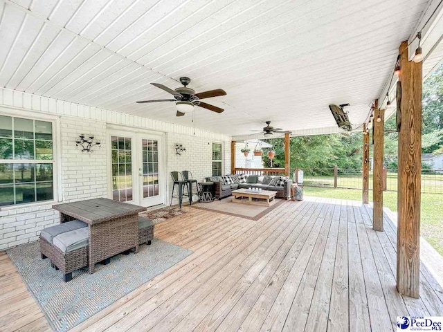 wooden terrace featuring outdoor lounge area, ceiling fan, french doors, and fence
