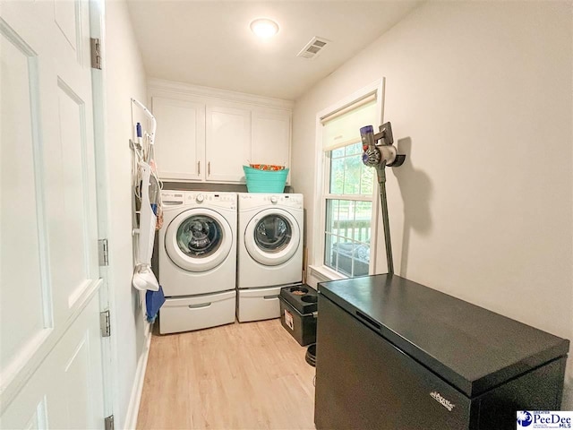 laundry room with washer and clothes dryer, cabinet space, and light wood-type flooring