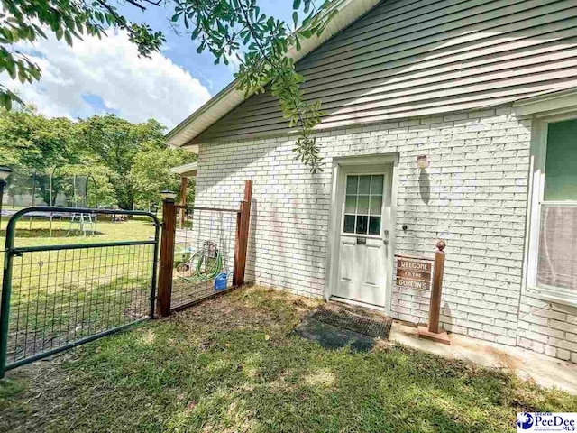 entrance to property featuring brick siding and a lawn