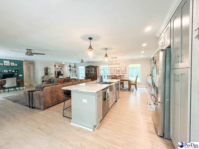 kitchen with appliances with stainless steel finishes, light wood-style flooring, a breakfast bar area, a kitchen island with sink, and recessed lighting