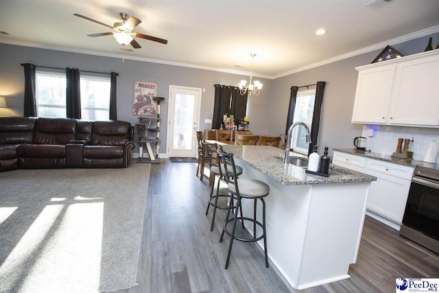 kitchen with a kitchen island with sink, sink, white cabinets, and decorative light fixtures