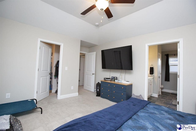 bedroom with ceiling fan, light colored carpet, and ensuite bathroom