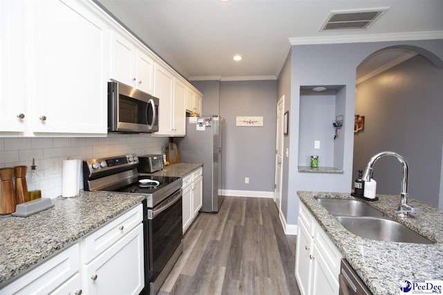 kitchen with sink, light stone counters, crown molding, stainless steel appliances, and white cabinets