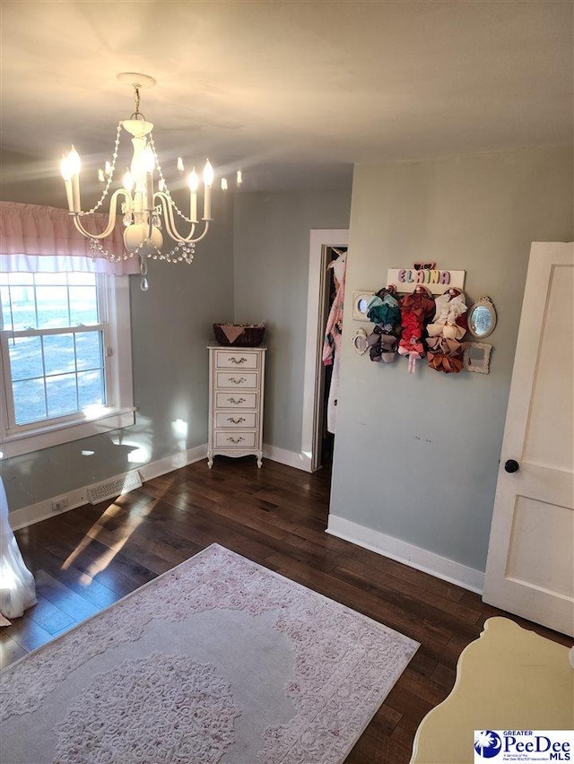 unfurnished bedroom featuring an inviting chandelier and dark hardwood / wood-style flooring