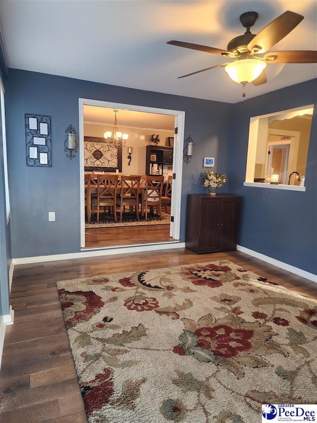 living room featuring ceiling fan with notable chandelier and dark wood-type flooring