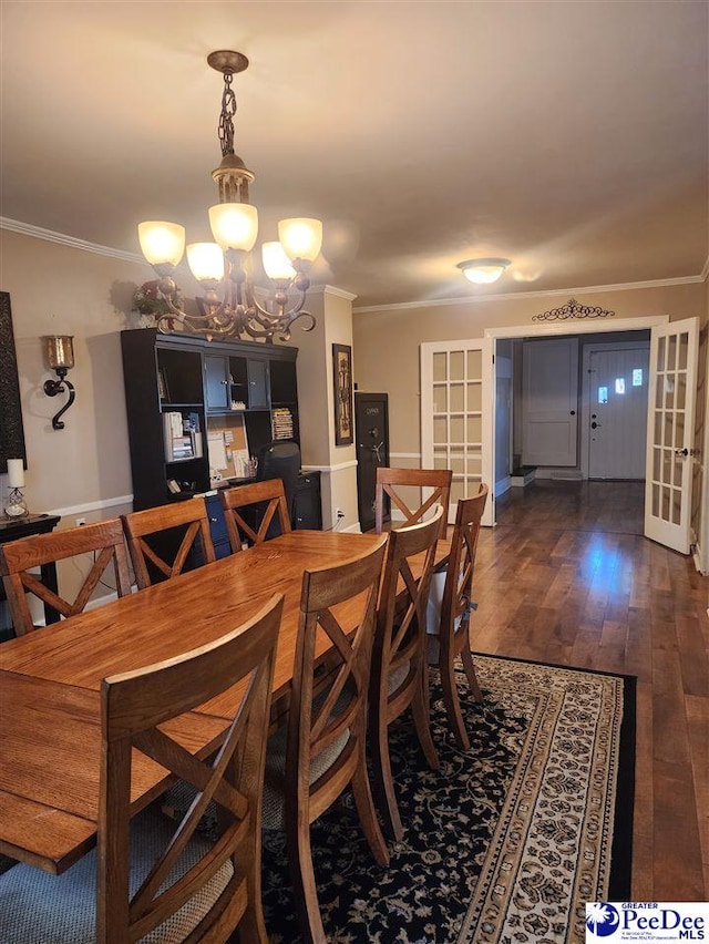 dining room with crown molding, dark wood-type flooring, and an inviting chandelier