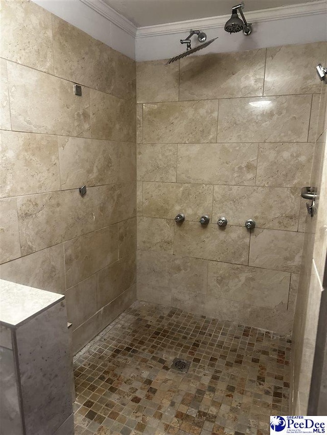 bathroom with ornamental molding and tiled shower