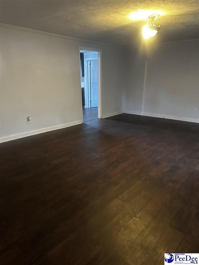 spare room featuring dark wood-style floors, a textured ceiling, and baseboards