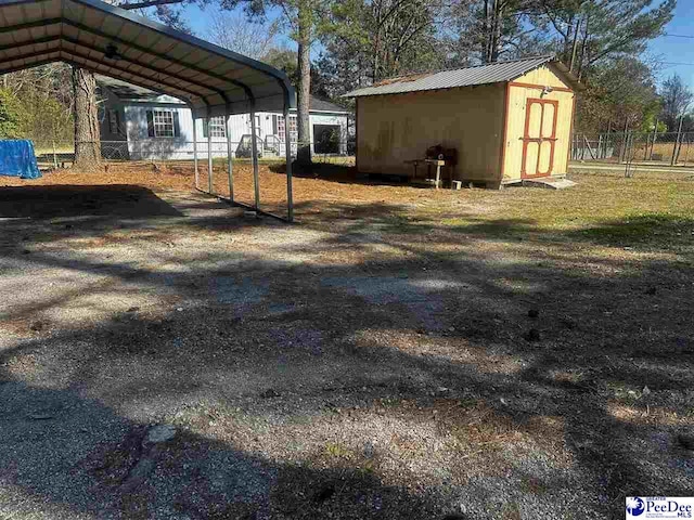 view of yard featuring a storage shed, fence, an outbuilding, and a detached carport