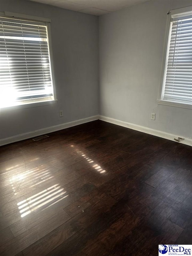 spare room featuring dark wood-style floors and baseboards