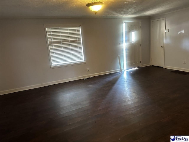 spare room with dark wood-type flooring, a textured ceiling, and baseboards