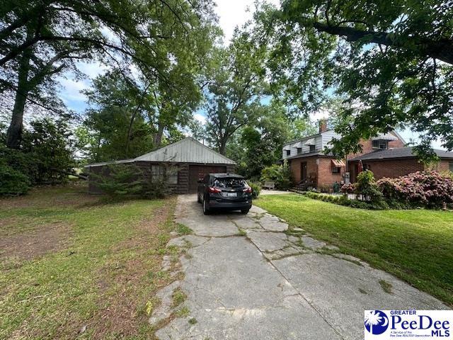 view of side of home featuring driveway, a yard, a garage, and a chimney