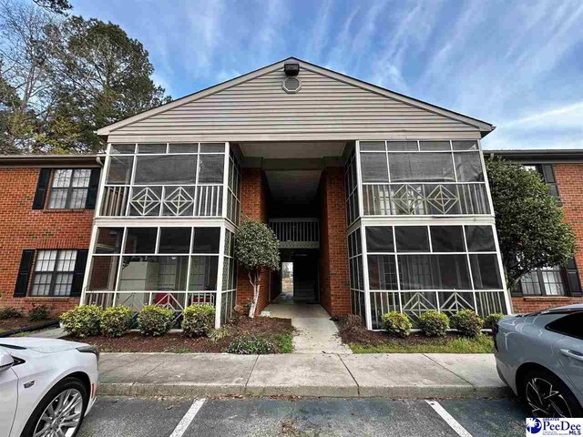 1215-G Brittany Dr, Florence, SC 29501 - view of front of house with brick siding, a sunroom, and uncovered parking