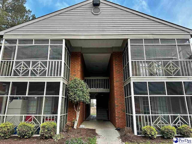 view of front of property with brick siding and a sunroom