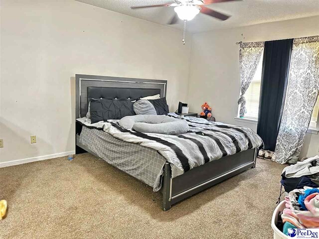 carpeted bedroom featuring baseboards, ceiling fan, and a textured ceiling