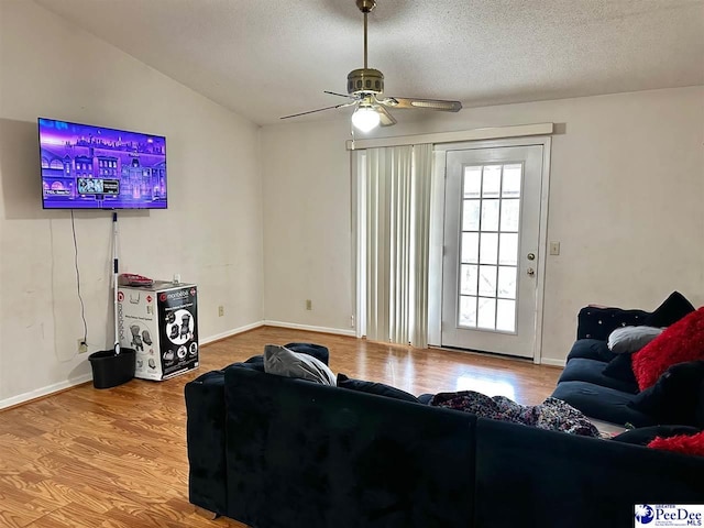 living room with baseboards, a textured ceiling, wood finished floors, and a ceiling fan