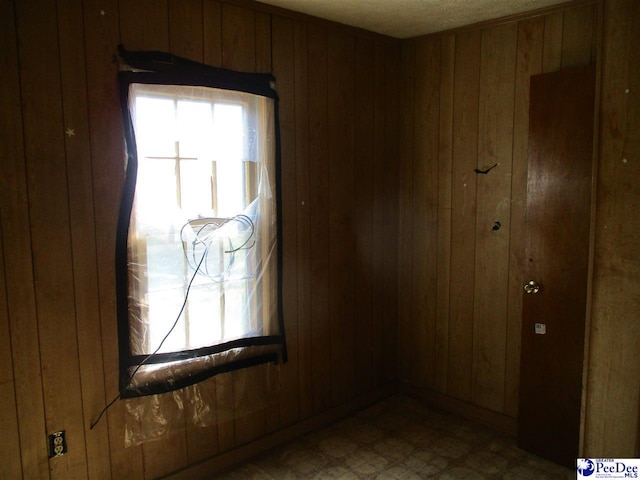 unfurnished room featuring wooden walls