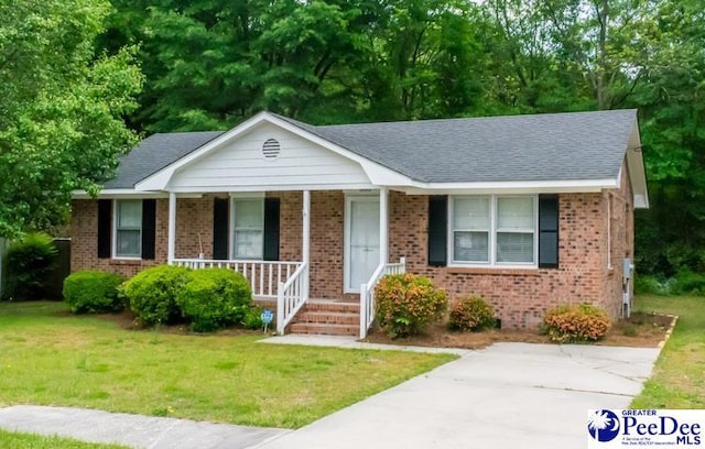 view of front of home featuring covered porch, brick siding, and a front yard