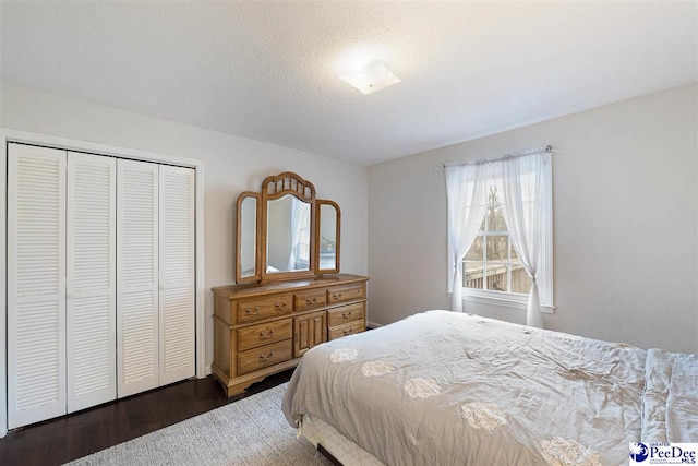 bedroom with dark wood-type flooring, a closet, and a textured ceiling