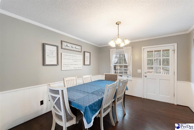 dining space featuring ornamental molding, dark hardwood / wood-style flooring, a textured ceiling, and a notable chandelier