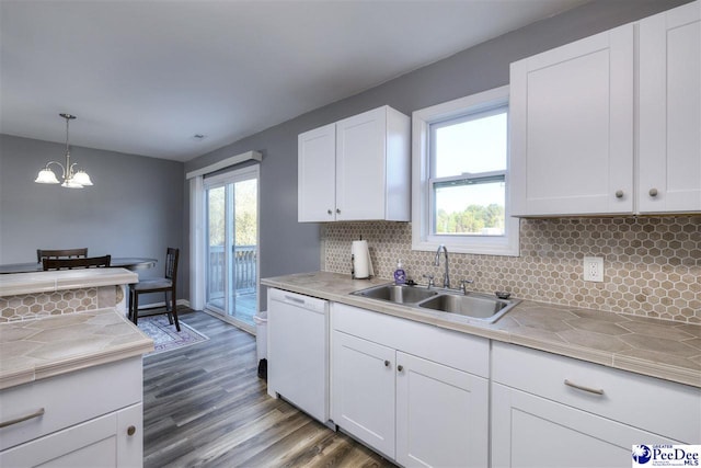 kitchen featuring tile countertops, wood finished floors, white cabinets, white dishwasher, and a sink