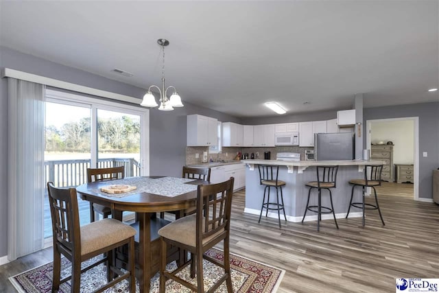 dining room featuring a notable chandelier, light wood-style floors, visible vents, and baseboards