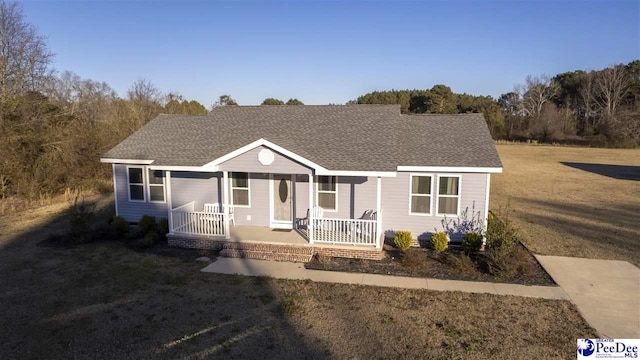 view of front of house with a porch, a shingled roof, and a front lawn